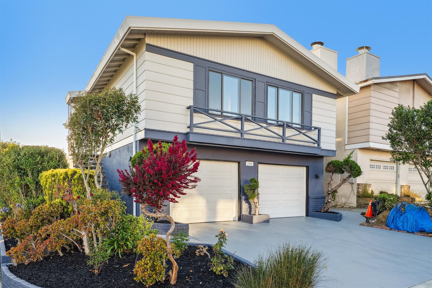 Finished two-story home with new siding, white garage doors, balcony railing and planted front beds, Shipley Avenue, Daly City