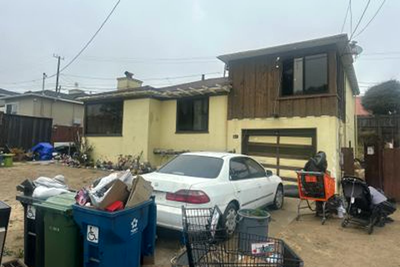 The same house before renovation: fire-damaged, with a debris-filled driveway
